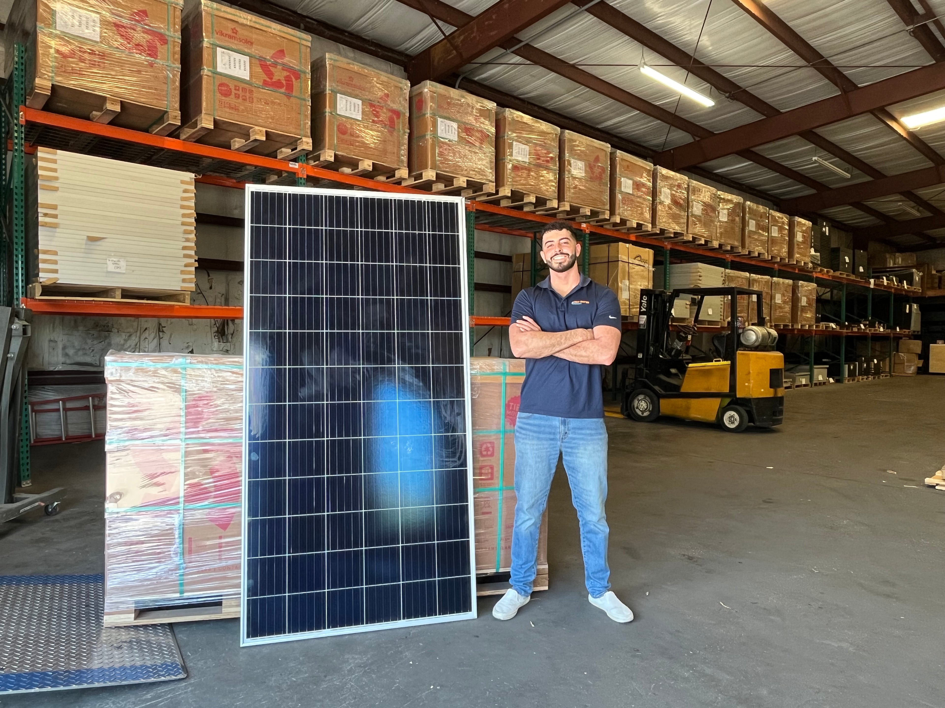 Man standing next to a solar panel in a warehouse setting